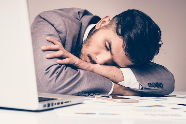 Foto giovane che dorme davanti al portatile al tavolo dell'ufficio