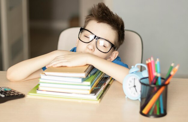 Giovane che dorme con i libri al tavolo in camera