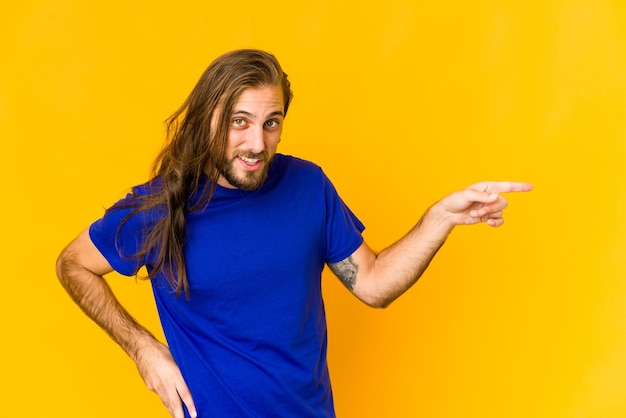 Photo young man smiling cheerfully pointing with forefinger away