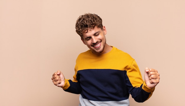 Young man smiling, feeling carefree, relaxed and happy, dancing and listening to music, having fun at a party