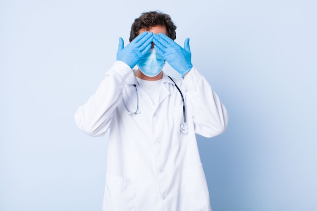 Young man smiling and feeling happy, covering eyes with both hands and waiting for unbelievable surprise. coronavirus concept