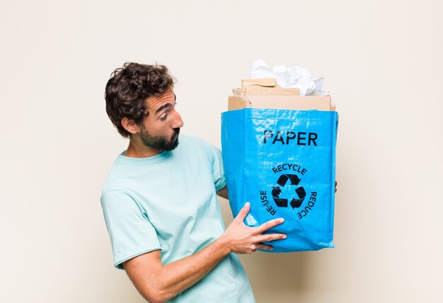 Young man smiling, feeling happy, positive and satisfied, holding or showing object or concept on copy space