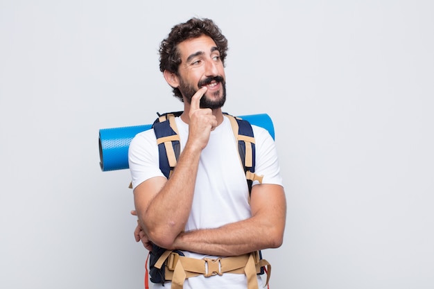 Foto giovane uomo sorridente felicemente e fantasticando o dubitando, guardando al lato