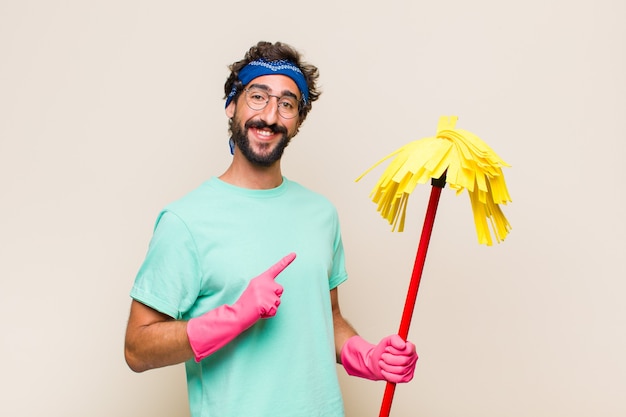 Young man smiling happily and pointing to side and upwards with both hands showing object in copy space