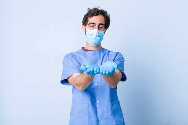 Young man smiling happily with friendly, confident, positive look, offering and showing an object or concept. coronavirus concept