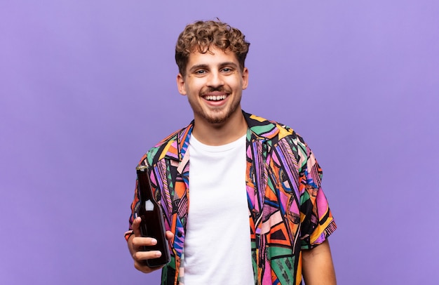 Young man smiling happily with a hand on hip and confident, positive, proud and friendly attitude.