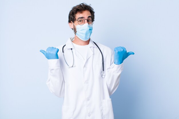 Young man smiling joyfully and looking happy, feeling carefree and positive with both thumbs up. coronavirus concept