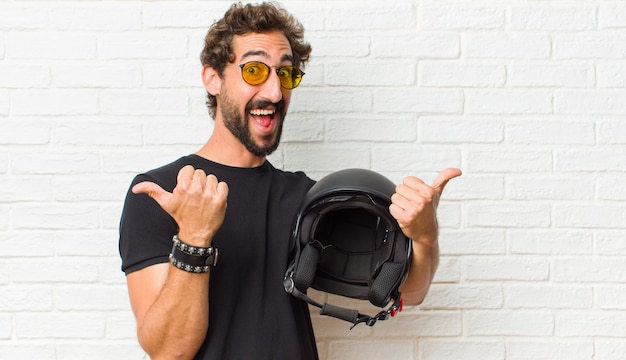 Young man smiling joyfully and looking happy, feeling carefree and positive with both thumbs up