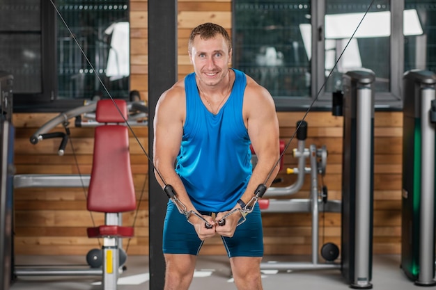 A young man smiling looking at the camera in a blue shirt in the gym Sports concept healthy lifestyle