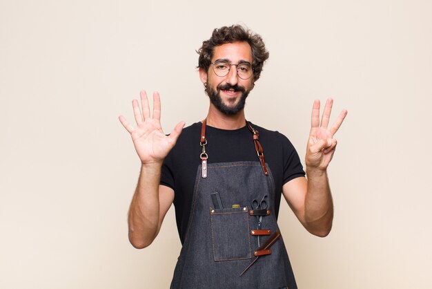 Young man smiling and looking friendly, showing number eight or eighth with hand forward, counting down