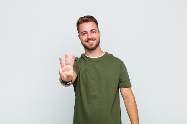 Young man smiling and looking friendly, showing number one or first with hand forward, counting down