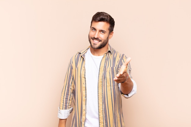 Young man smiling, looking happy, confident and friendly, offering a handshake to close a deal