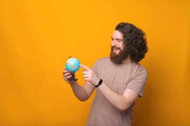 young man smiling and pointing at globe, next point to travel