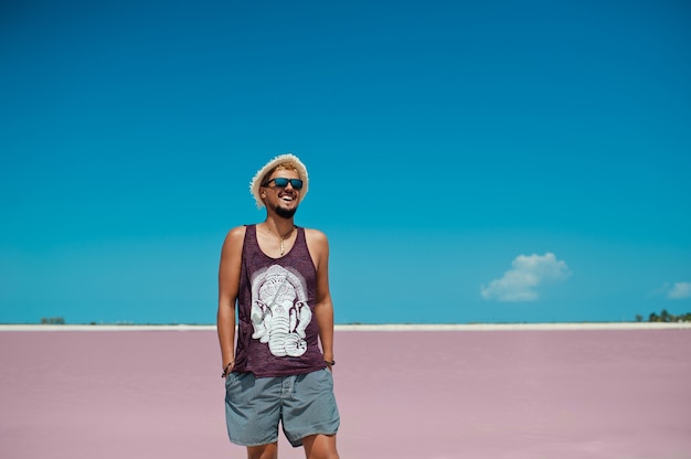 Young man smiling and posing against pink salt lake in las coloradas mexico