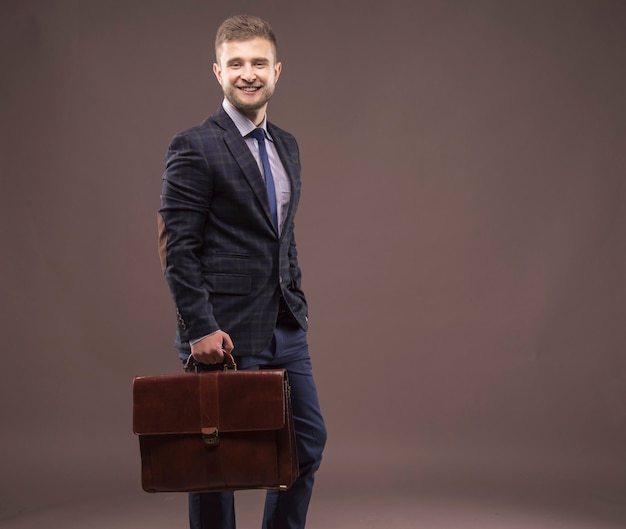 Photo young man smiling in a suit with a briefcase in his hands