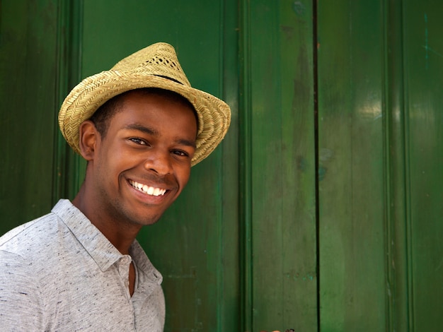 Young man smiling with hat on green background 