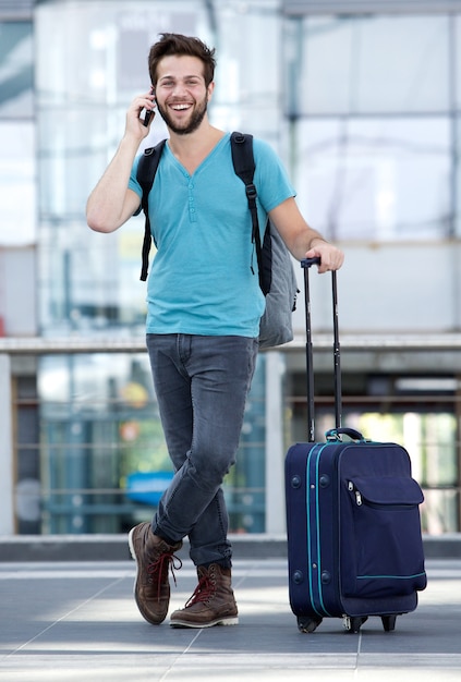 Young man smiling with suitcase at airport