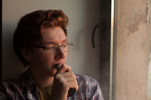 Photo young man smoking electronic cigarette.