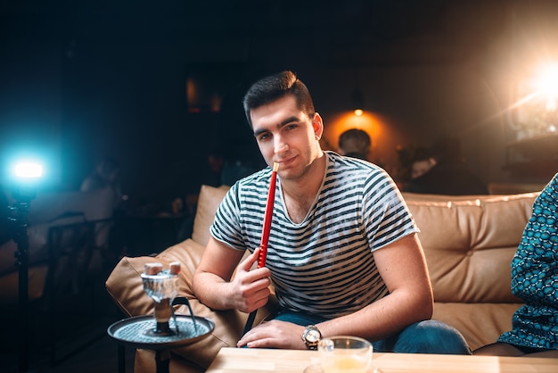 Young man smoking and relaxation at hookah bar