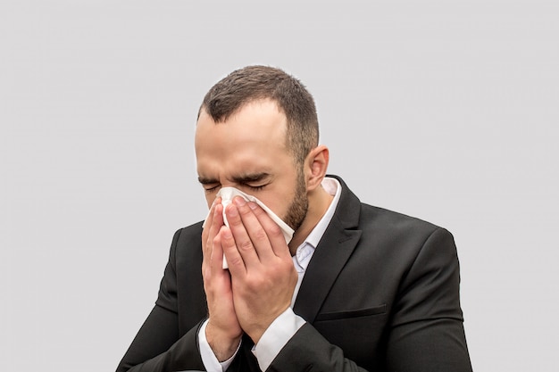 Young man sneez into white tissue. He keeps eyes closed. Young man is sick. 