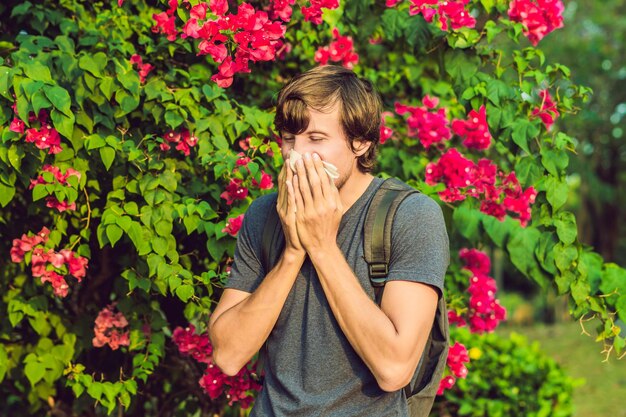 Young man sneezes because of an allergy to pollen