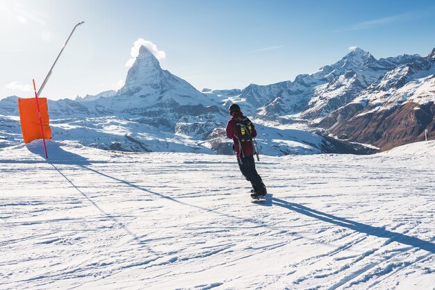 Young man snowboarding in zermatt ski resort right next to the famous matterhorn peak