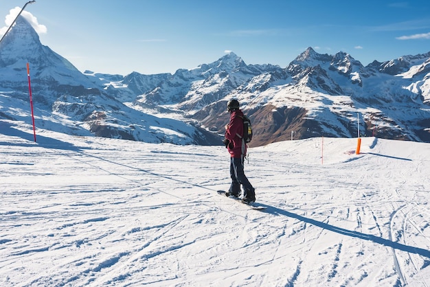 Young man snowboarding in zermatt ski resort right next to the famous matterhorn peak