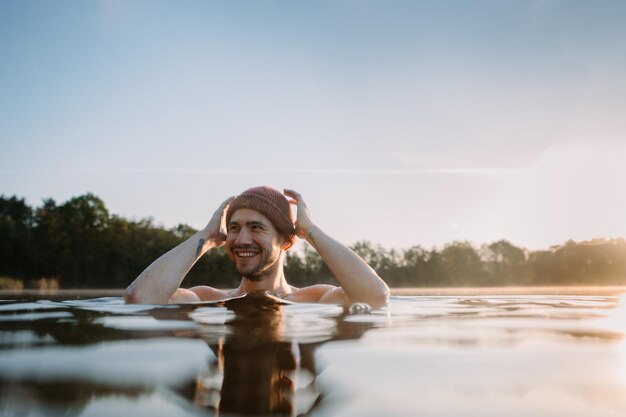 Young man soaks in the winter lake at morning Male person taking care of his health