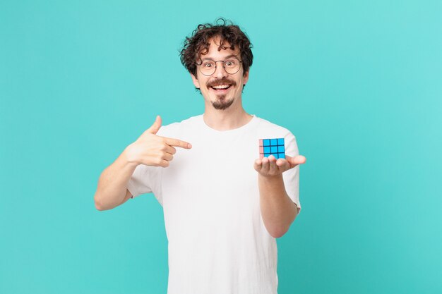 Young man solving an intelligence problem feeling happy and pointing to self with an excited