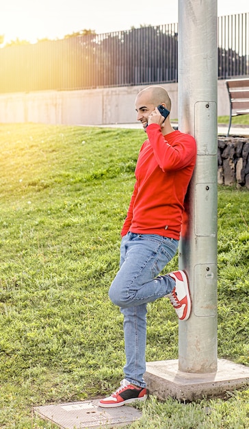 写真 公園の電話で話している若い男、笑顔