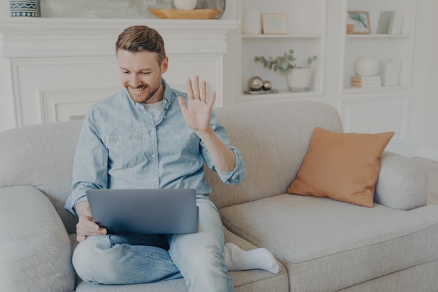 Young man speaking with family using notebook while sitting on couch