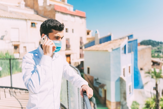 Il giovane parla al telefono con una mascherina medica