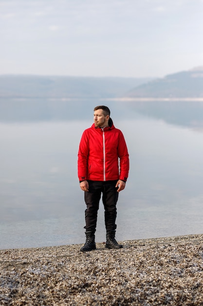 A young man in a sports suit stands by the river