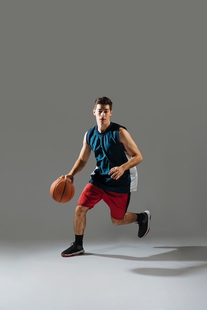 Photo young man in sportswear playing basketball