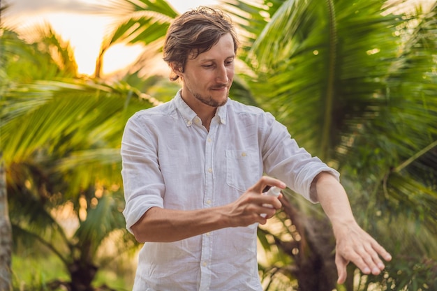 Young man spraying mosquito insect repellent in the forrest insect protection