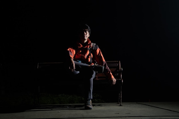 Young man standing against black background at night