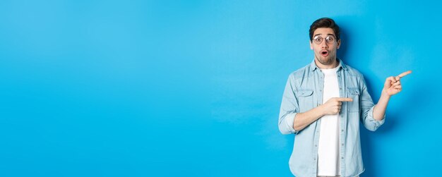 Young man standing against blue background