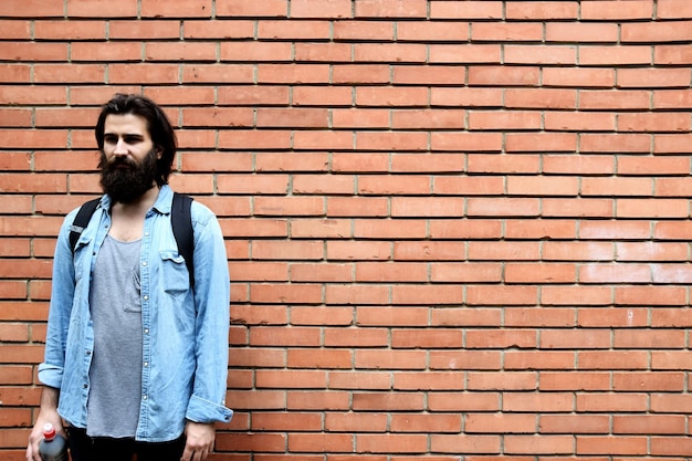 Photo young man standing against brick wall