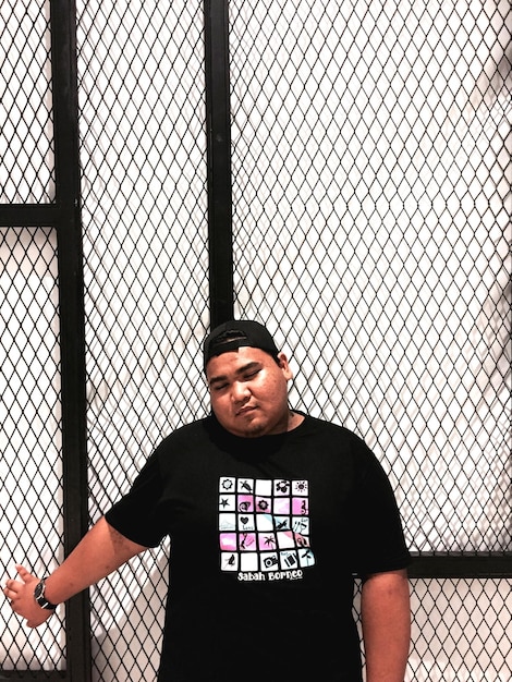 Photo young man standing against metal grate