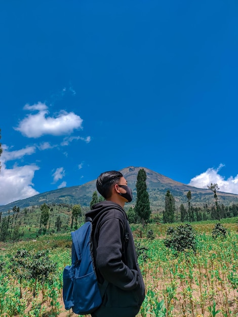 山と空に向かって立っている若い男