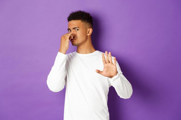 Young man standing against purple background