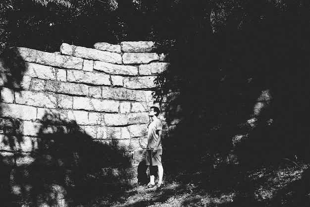 young man standing against stone wall on field