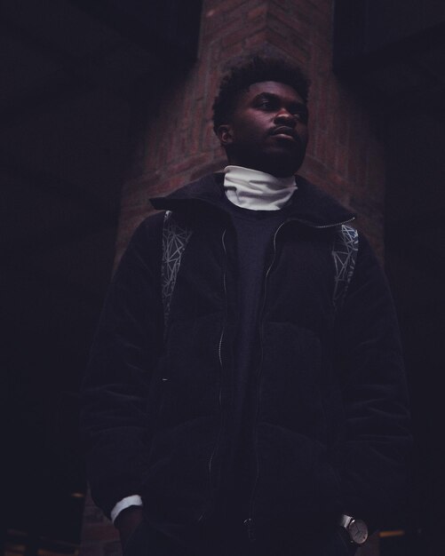 Photo young man standing against wall at night