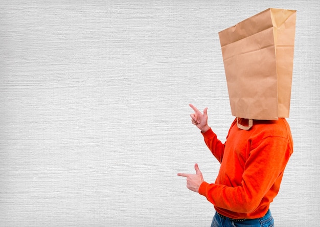 Фото Молодой человек стоит и жестикулирует с экологическим бумажным пакетом на голове