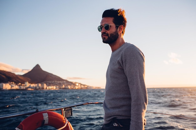 Young man standing in boat on sea against sky