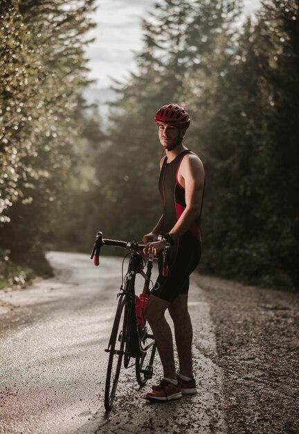 道路で自転車のそばに立っている若い男