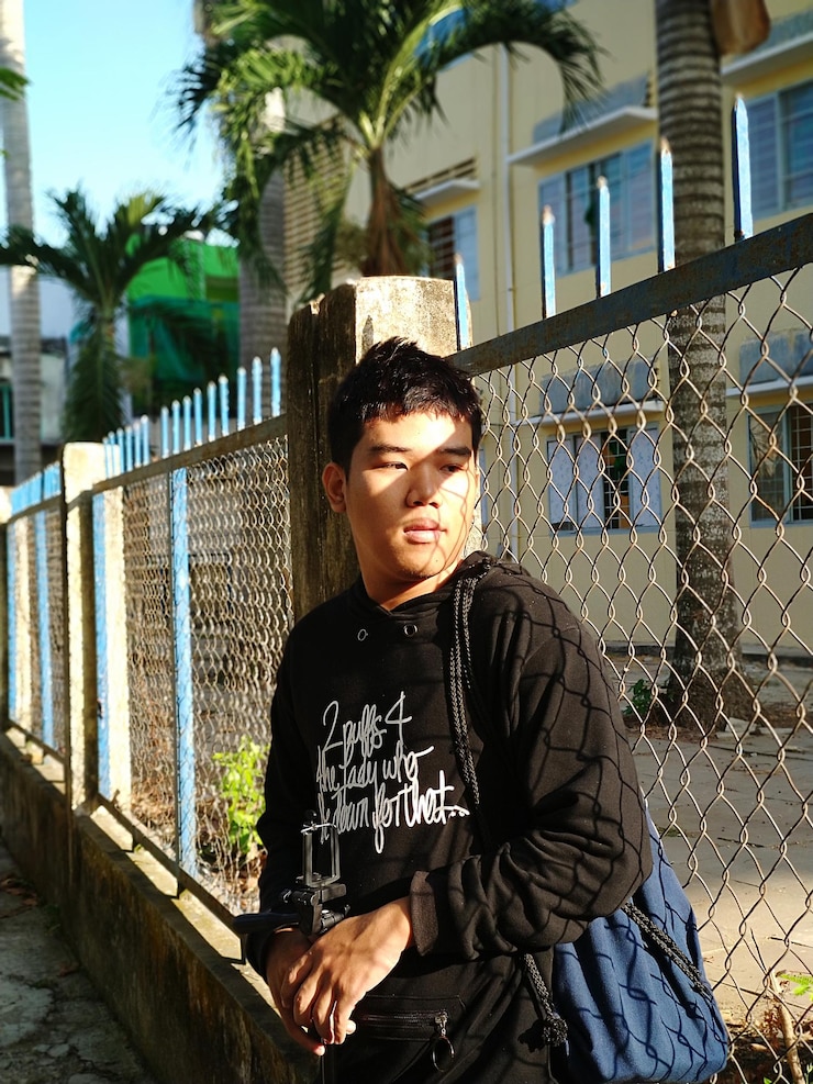 Photo 木の反対側のフェンスに立っている若い男