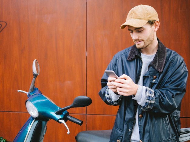 市内でスクーターのそばに立っている若い男