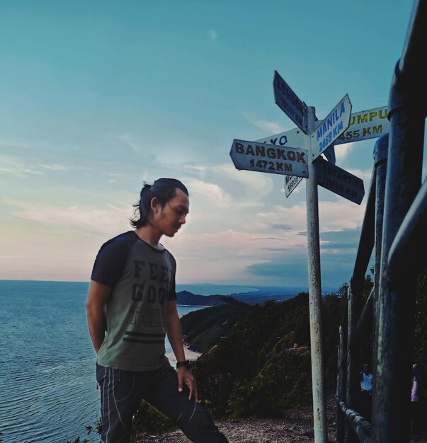 Young man standing by sea against sky