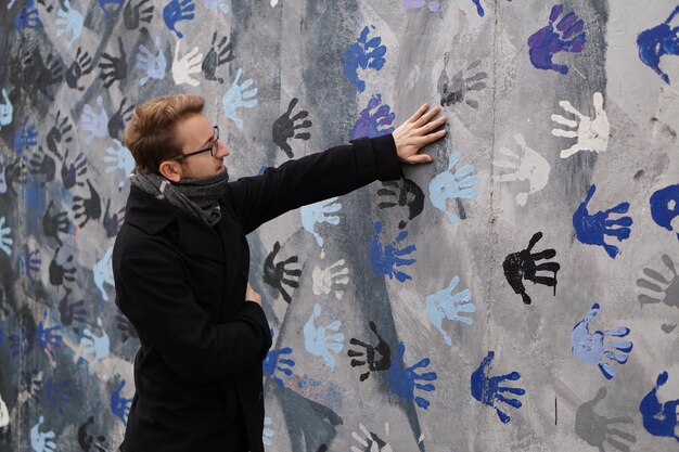 Photo young man standing by wall with hand prints